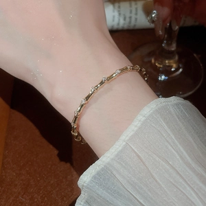 Detailed view of a gold bamboo-style bracelet with sparkling zircon stones on a female wrist