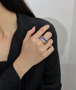 Close-up of a double-row multi-colored gemstone ring worn by a model in a black blazer
