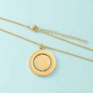 Detailed view of golden rotatable double-layer circular pendant necklace on blue background