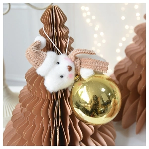 Detail of plush white bear ornament with knit hat and golden bauble on a paper tree