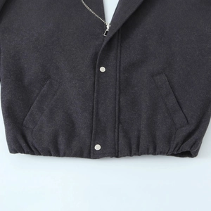 Close-up of charcoal grey wool bomber jacket with metal zipper and ribbed hem details