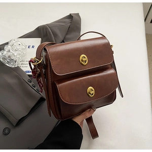 Detail of vintage brown leather crossbody bag with dual pockets and gold twist locks