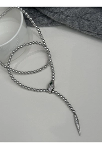 Macro shot of silver beaded Y-necklace featuring a zircon-encrusted serpent head charm