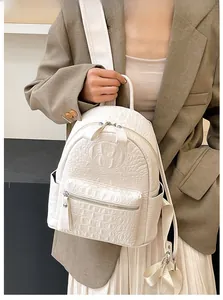 Detail shot of ivory croc-embossed texture and silver zipper on the minimalist backpack