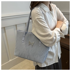 Close-up of light blue pleated tote bag featuring a silver butterfly hardware detail
