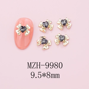 Macro detail of 9.5x8mm bow nail charms with black heart crystal and gold alloy base