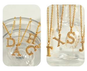 Close-up of elegant gold titanium steel necklaces with sparkling crystal alphabet pendants