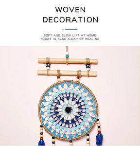 Detail of bohemian evil eye dreamcatcher with blue tassels and wooden beads on pink wall
