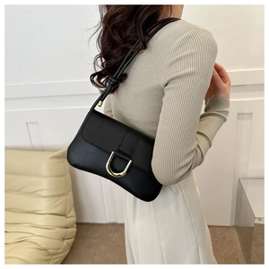 Detail of a black leather underarm bag with a gold horseshoe buckle on a beige knit sweater