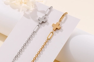 Detailed view of two-tone gold and silver cross chain bracelets on a minimalist background