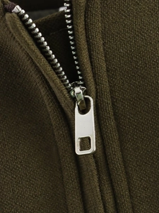 Macro shot of durable silver metal zipper on dark olive green knitted fabric vest