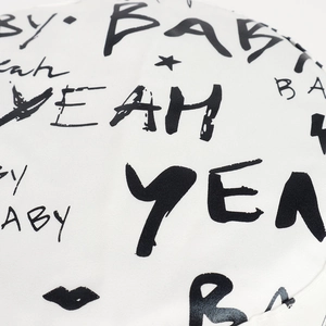 Close-up of white canvas bucket hat featuring black graffiti letters and star graphics