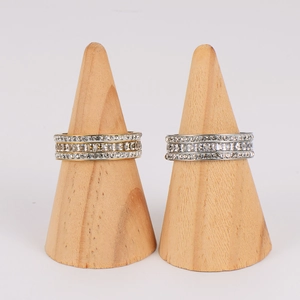 Elegantes anillos de acero inoxidable con circonitas en oro y plata sobre madera