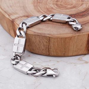 Vue détaillée d'un bracelet gourmette argenté avec croix serties sur support en bois