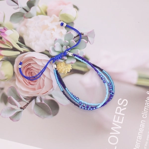 Detail of bohemian triple-layered blue beaded bracelet with adjustable woven cords