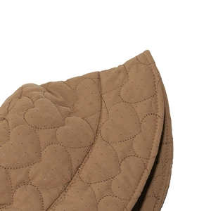 Close-up of khaki quilted winter hat featuring embroidered heart patterns and gold glitter