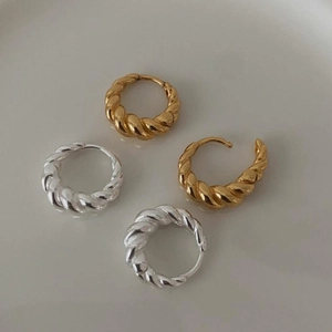 Macro shot of 925 sterling silver twist hoop earrings in polished gold and silver finishes
