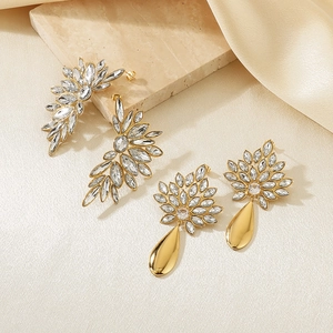 Detail of vintage gold leaf earrings with rhinestones on beige stone and silk background