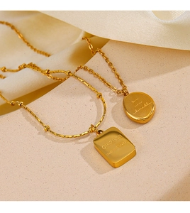 Close-up of 18K gold plated necklaces featuring CHARM engraving and silk fabric background