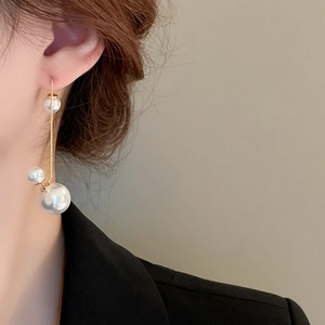 Close-up of golden tassel pearl earrings showing the dual-wear style on a fashion model