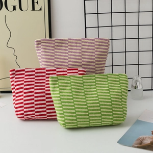 Detailed knit texture of checkered and striped makeup bags on a modern white surface
