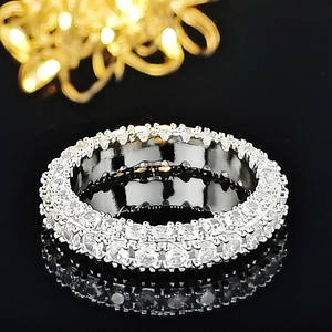 Close-up of a wide silver band ring featuring multiple rows of pavé-set round cubic zirconia