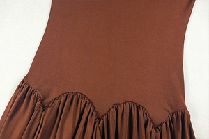 Close-up of wavy waist seam and dense pleated design on brown slim-fit dress