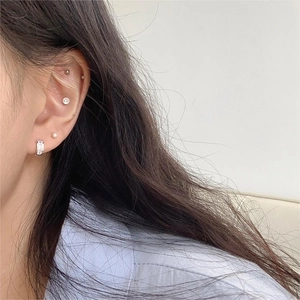 Close-up of minimalist 925 sterling silver hoop and zircon stud earrings on model ear