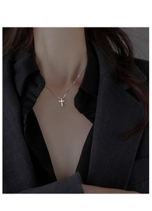 Close-up of a silver cross necklace worn by a model in elegant suit for styling