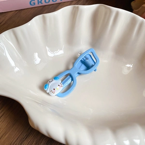 Detailed close-up of a light blue cartoon cat hair clip on a white shell plate