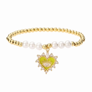 Close-up of beaded pearl bracelet with heart devil eye pendant in gold and green