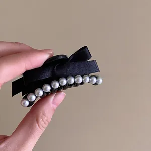 Detailed shot of French black ribbon bow hair clip with elegant pearl embellishments