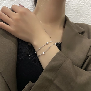 Close-up of double-layered silver bracelet with star charms on a model's wrist