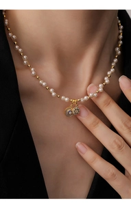 Détail d'un collier de perles plaqué or 18 carats avec pendentifs ronds en zircon sur modèle