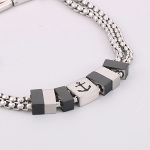 Dettagli macro del bracciale doppio in acciaio con perline quadrate e motivo ad ancora