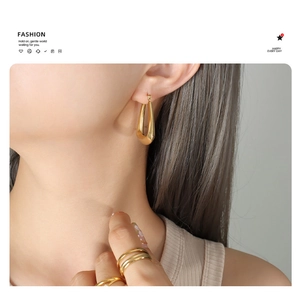 Detail view of glossy 18k gold plated U-shaped earrings with minimalist metal rings