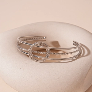 Macro shot of silver multi-layer cuff bracelet with twisted rope details and interlocked knot