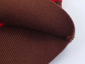 Gros plan sur la texture en maille côtelée marron avec détail de rayure rouge du polo