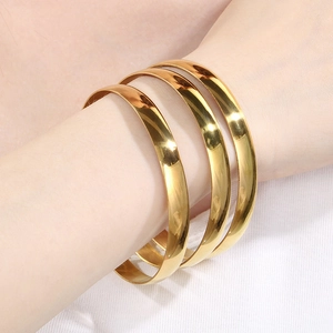 Close-up of three 8mm polished gold stainless steel bangles worn on a model's wrist