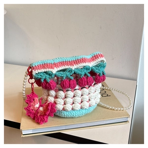 Detail of hand-crocheted bucket bag with cherry charms and elegant pearl strap