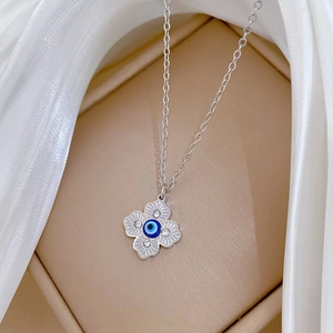 Macro detail of silver four-leaf clover pendant with blue evil eye and crystal inlays