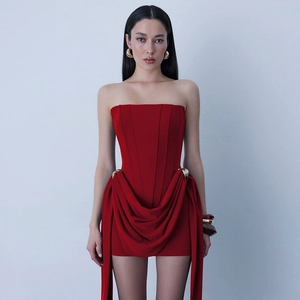 Detail of red strapless mini dress featuring elegant ruching and a metallic waist buckle
