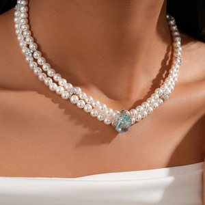 Macro view of double-layer pearl necklace featuring a large light blue gemstone pendant