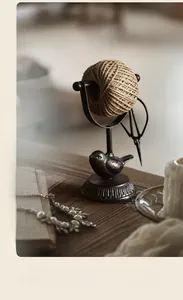 Close-up of vintage cast iron bird rope reel organizer with brown jute twine roll