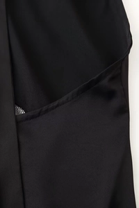 Dettaglio dell'abito in raso nero con delicate cuciture in pizzo sullo scollo