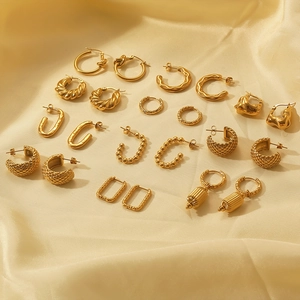 Close-up of gold C-shaped geometric earrings set on elegant beige silk fabric texture