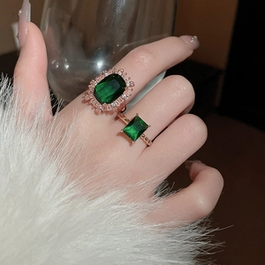 Detail of emerald green vintage style rings set in rose gold finish on model finger
