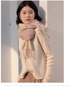 Detail of pink and beige plaid cashmere scarf with soft tassels on beige knit cardigan