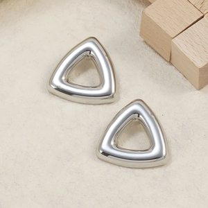 Detailed close-up of polished silver triangular stud earrings on a minimalist background