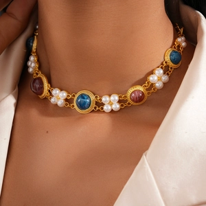 Close-up of vintage gold necklace featuring imitation pearls and resin gemstones